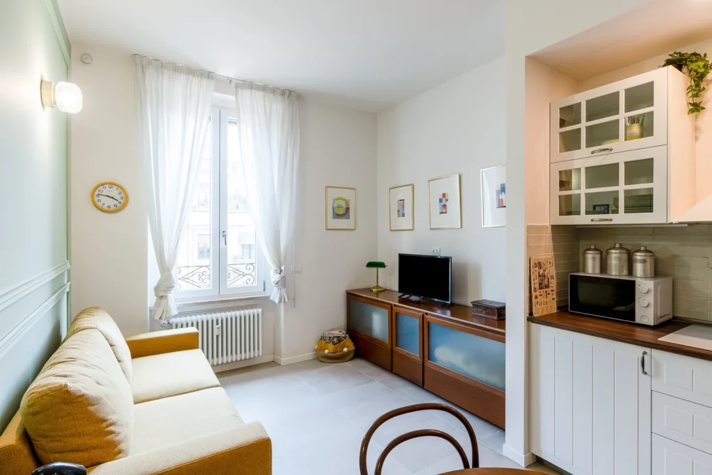 Living room with sofa, television, and large window in a Townhomes Milano Mid-Century Modern apartment in Milan.
