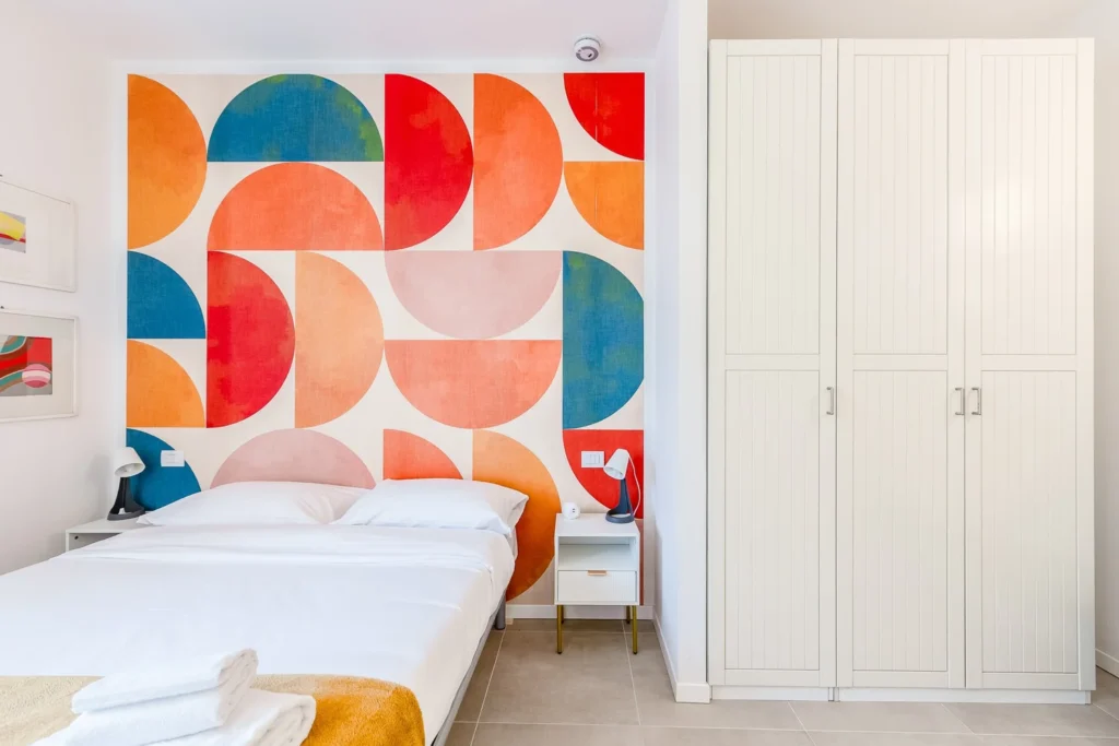 Cozy bedroom with abstract mural art and wardrobe in a Mid-Century Modern apartment by Townhomes Milano.