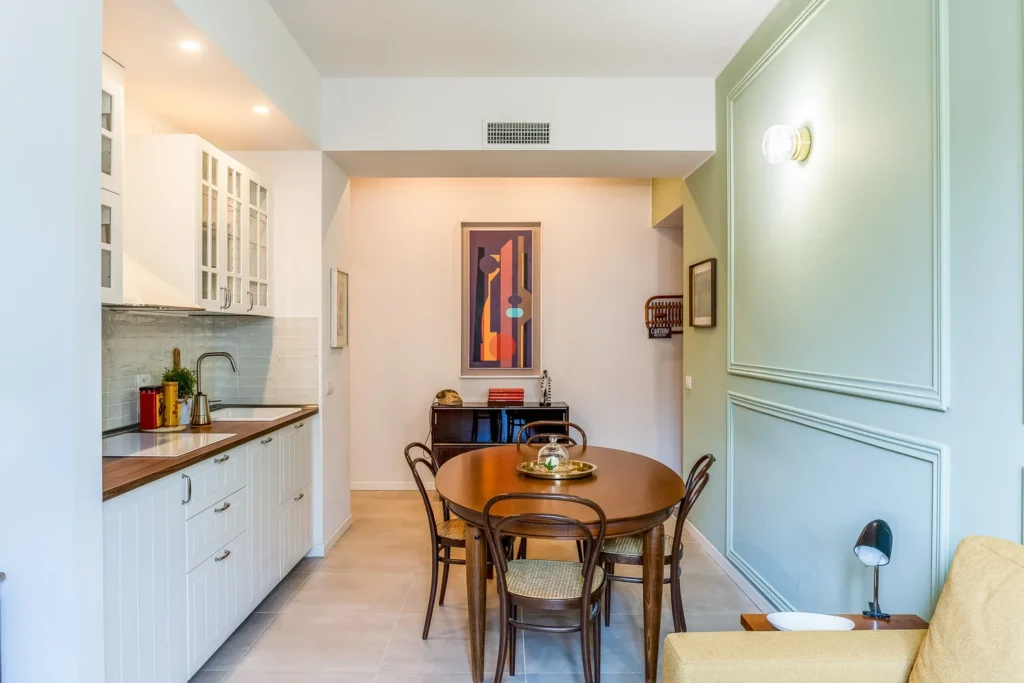 Warm dining nook with pendant lighting and compact kitchen in a Townhomes Milano Mid-Century Modern apartment.