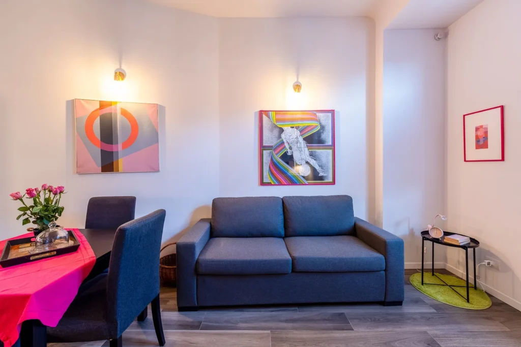 Comfortable living room with blue sofa, wall art, and warm lighting in the Colorful Eclectic apartment by Townhomes Milano.