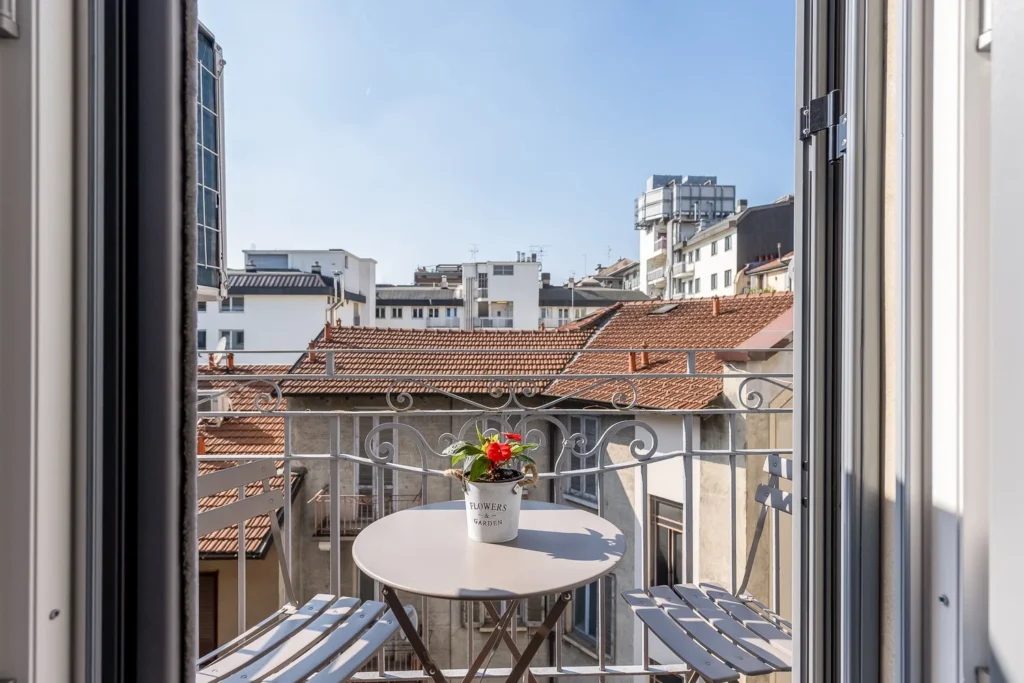Private balcony with small table and chairs overlooking Milan rooftops at Scandinavian Minimal Apartments by Townhomes Milano.