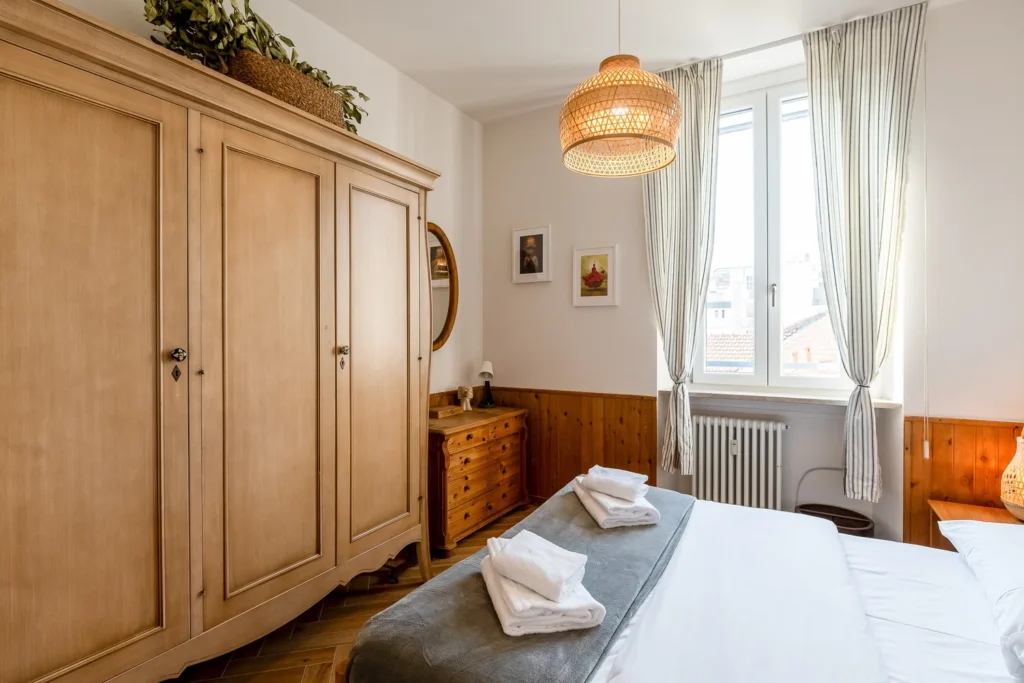Cozy bedroom with wooden wardrobe, bedside lamps, and neatly prepared beds in the Scandinavian minimal apartment by Townhomes Milano.