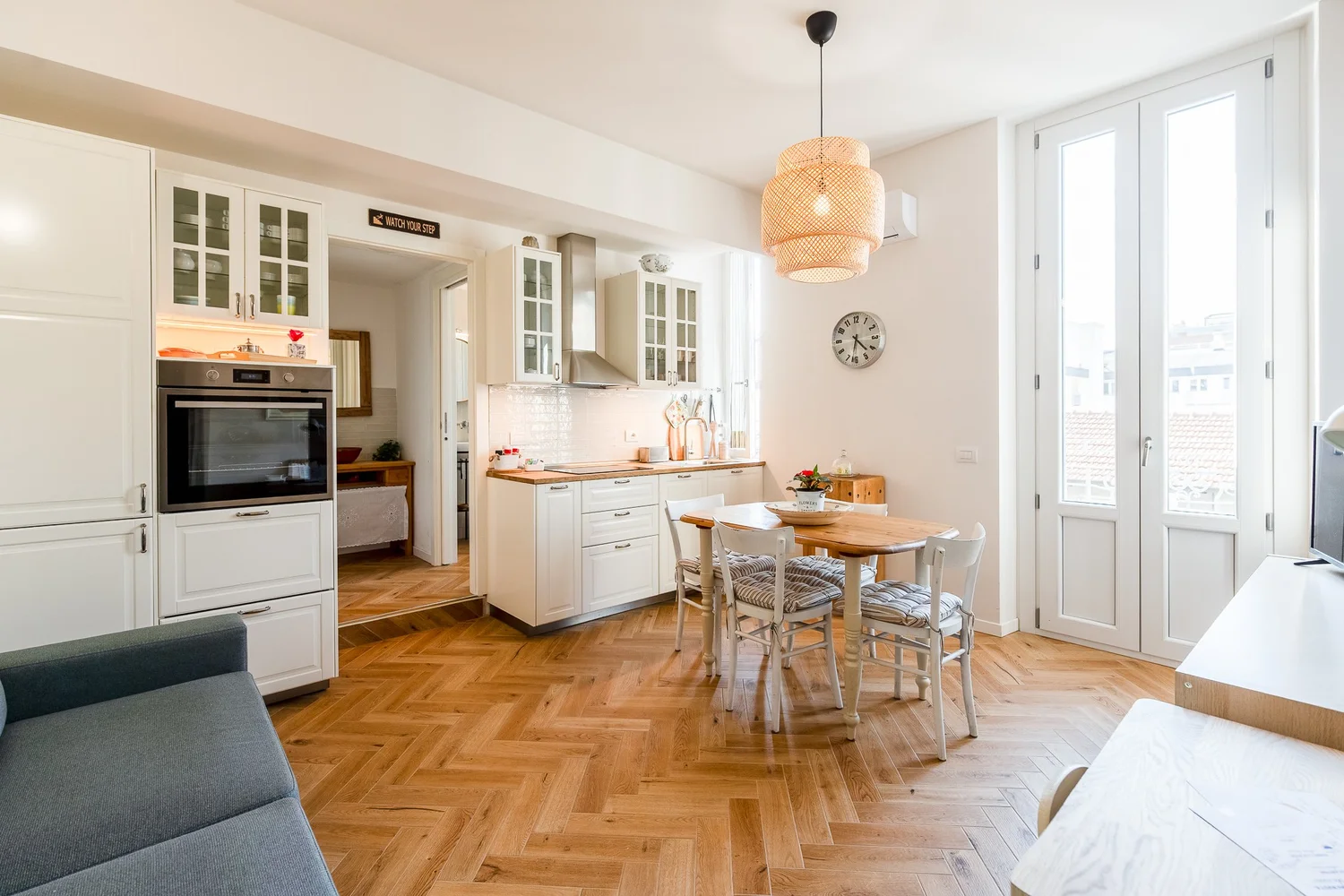 Spacious kitchen and dining area with wooden flooring, round dining table, and white cabinetry in Scandinavian Minimal Apartments by Townhomes Milano.
