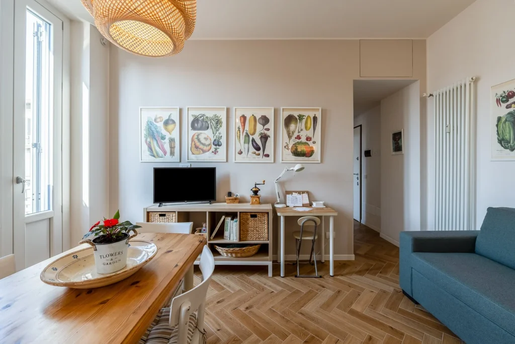 Open living and dining space with wooden table, television, and decorative wall art in Scandinavian Minimal Apartments by Townhomes Milano.