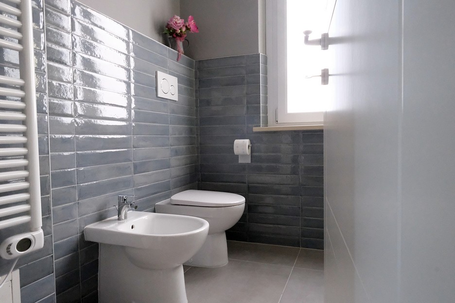 Modern bathroom with bidet toilet and grey tile walls reflecting the style of Casa Rosy