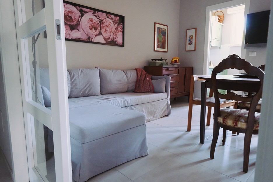 Bright living room with comfortable sofa and dining area reflecting the inviting style of Casa Rosy apartments in Diano Marina.