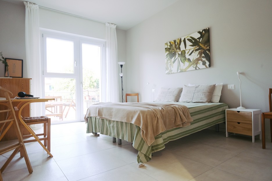 Bright bedroom with large window and soft bedding bringing natural light and calm at Casa Rosy apartments in Diano Marina.
