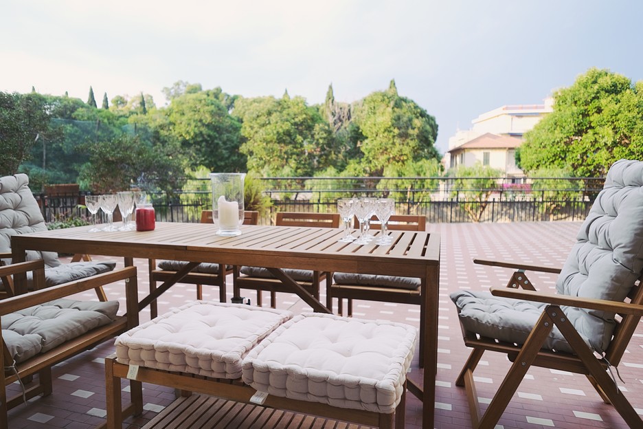 Outdoor dining area with wooden table and cushioned chairs offering a relaxing spot at Casa Rosy apartments in Diano Marina.