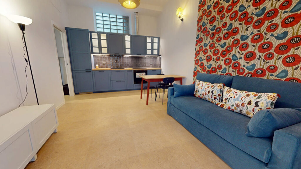 Living room with blue sofa and kitchen area at Simone Urban Organic apartment in Milan by Townhomes Milano.