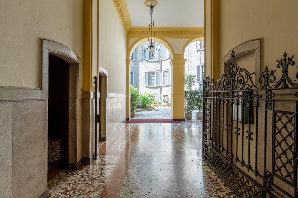 Milan apartment building entrance with decorative arches and tiled corridor at Townhomes Milano short-term stays
