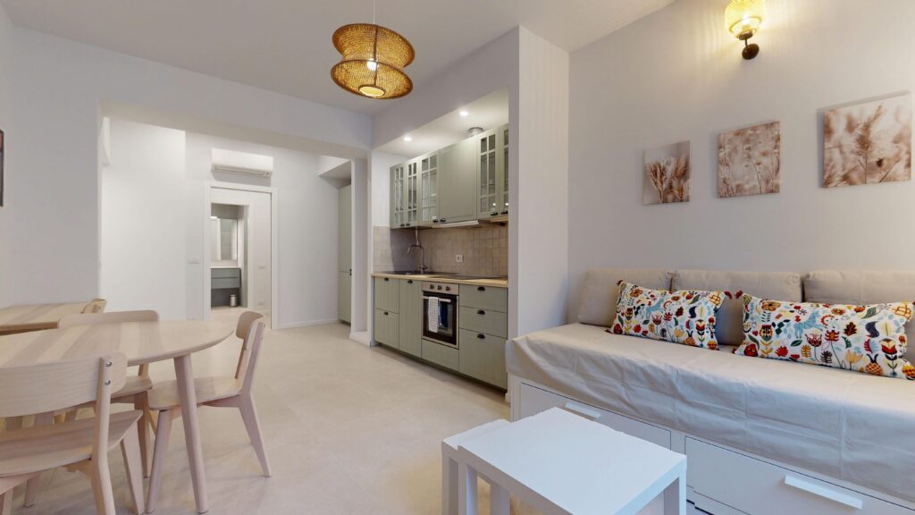 Perspective showcasing a contemporary kitchen with sage-green cabinetry and a comfortable daybed with patterned pillows in the apartment, for international tourists and travelers on a rental stay in Milan, Italy, managed by Townhomes Milano.