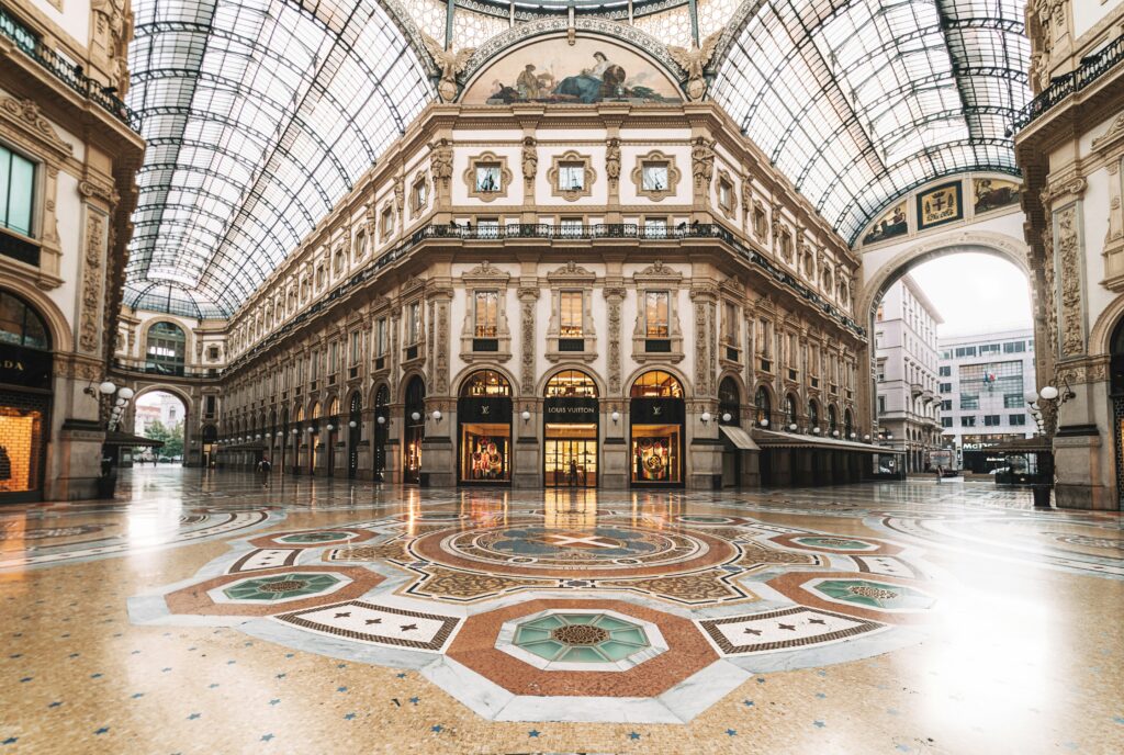 Historic Galleria Vittorio Emanuele II with ornate architecture, glass ceiling, and patterned marble floor