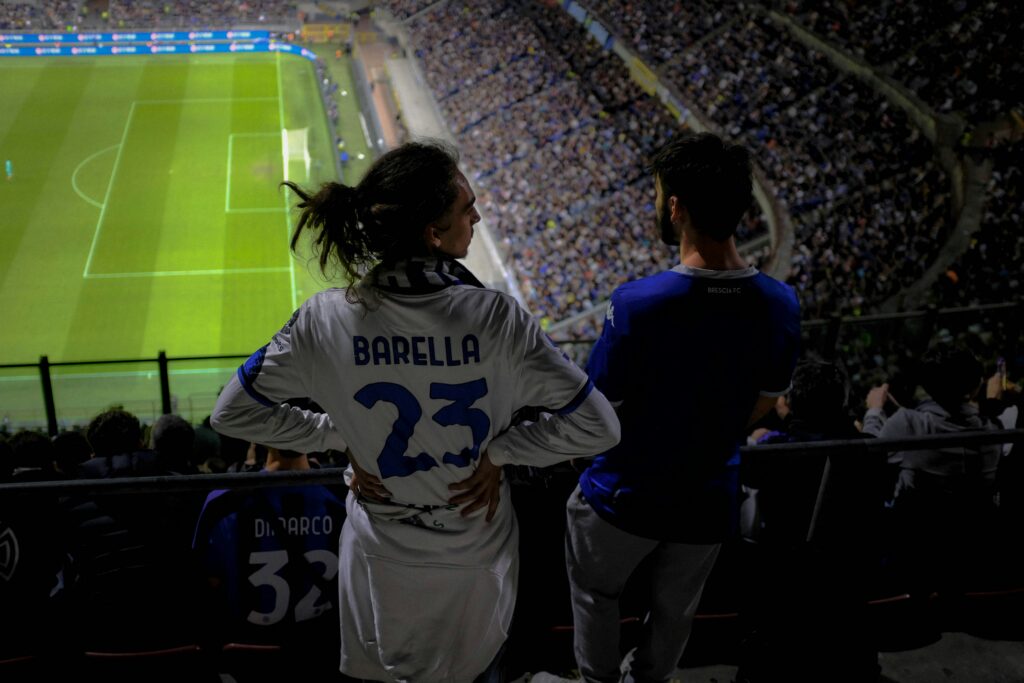 Football fans in stadium jerseys watching Inter Milan soccer match at packed venue