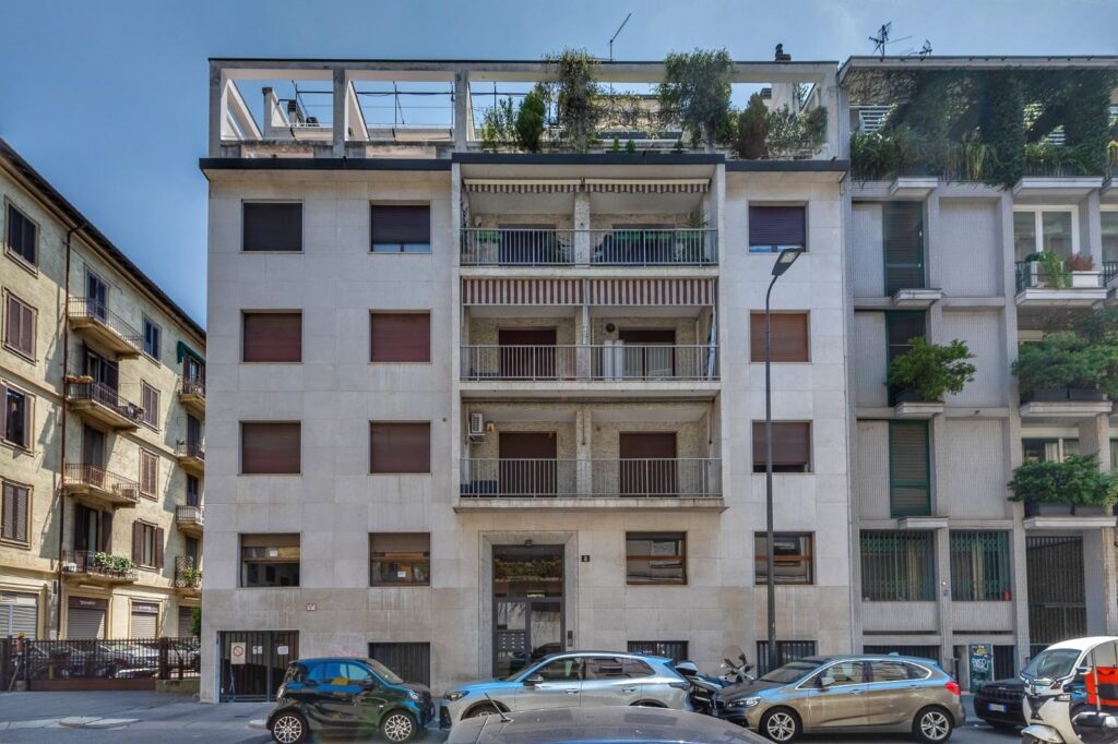 Modern Milan apartment building exterior with balconies, contemporary facade, and rooftop greenery