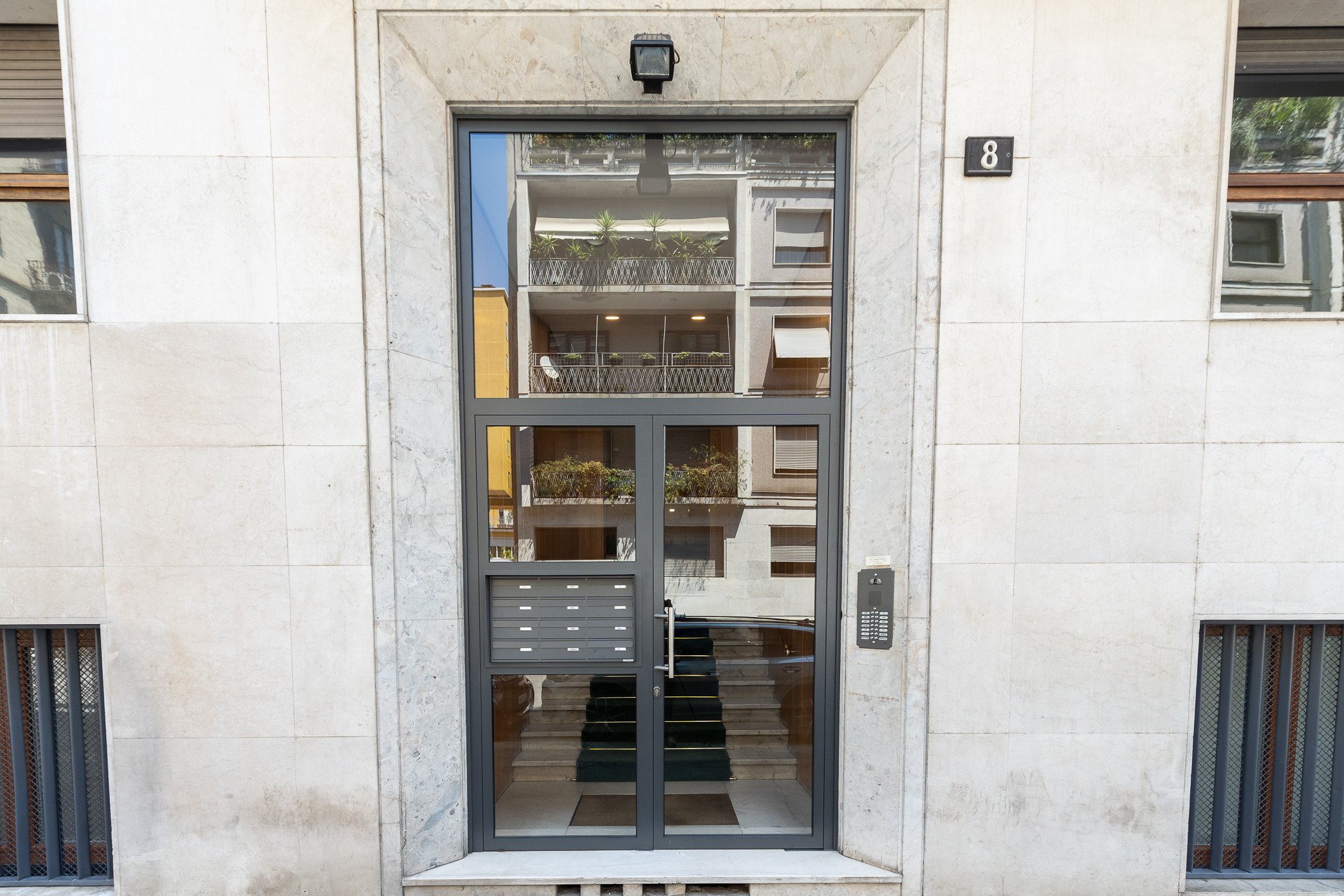Modern entrance of Via Razza 8 Town Homes Milano with glass doors and marble facade