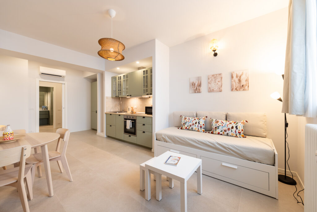 Studio apartment interior with integrated sleeping, dining, and kitchen areas in minimalist white design