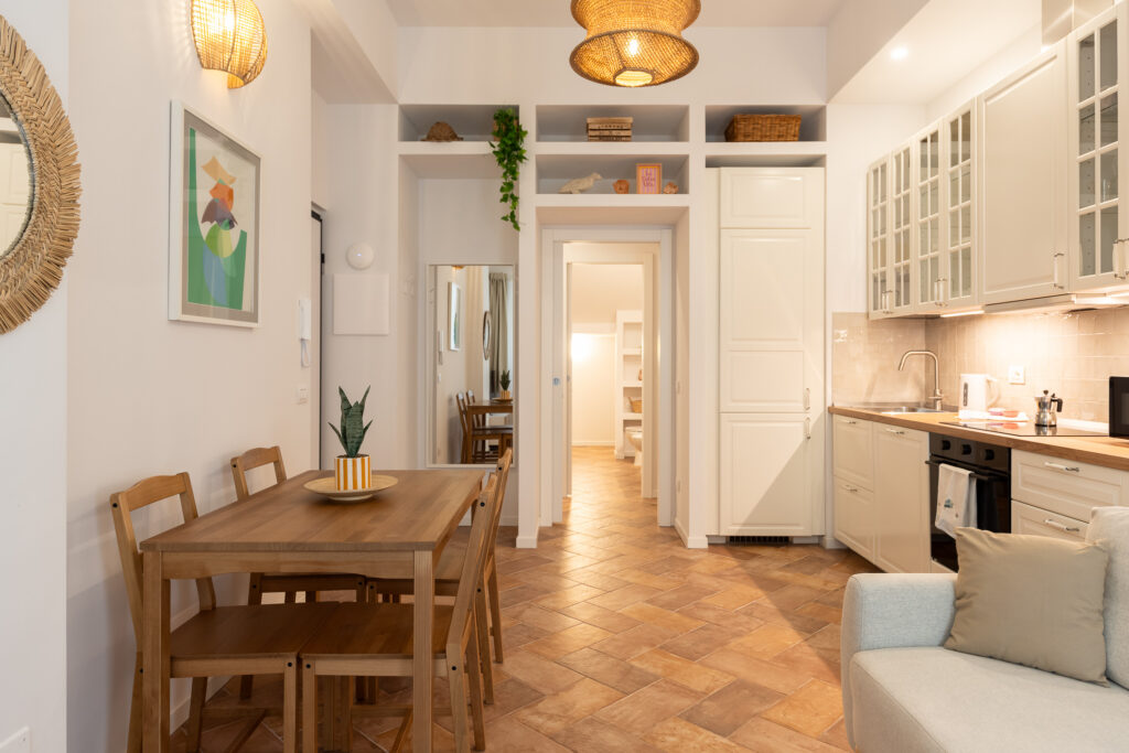 Bright dining area with cream kitchen, wooden table, and open-plan living space